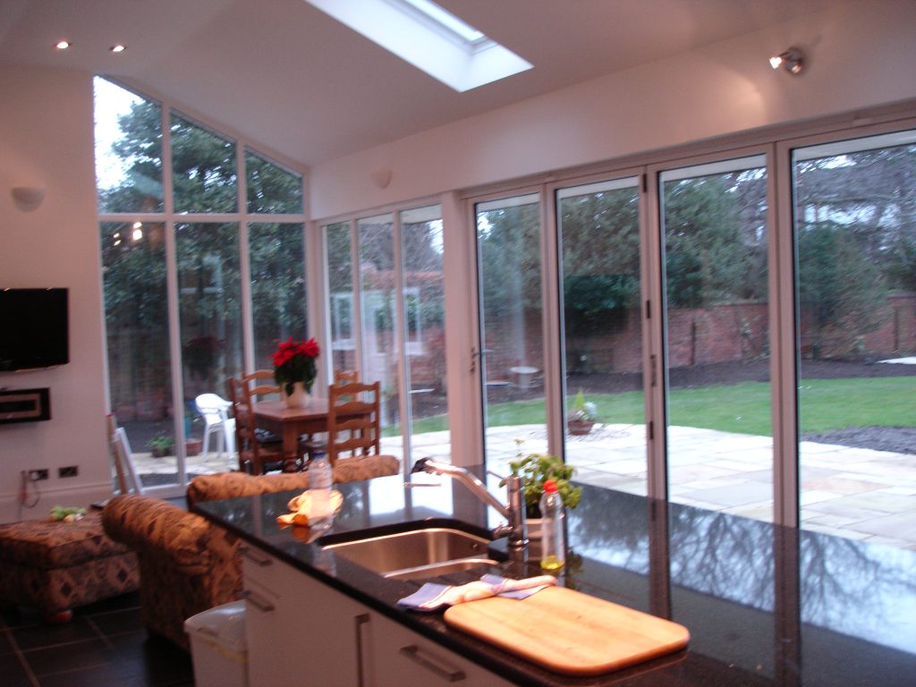 Kitchen island looking through to a glazed living space and garden