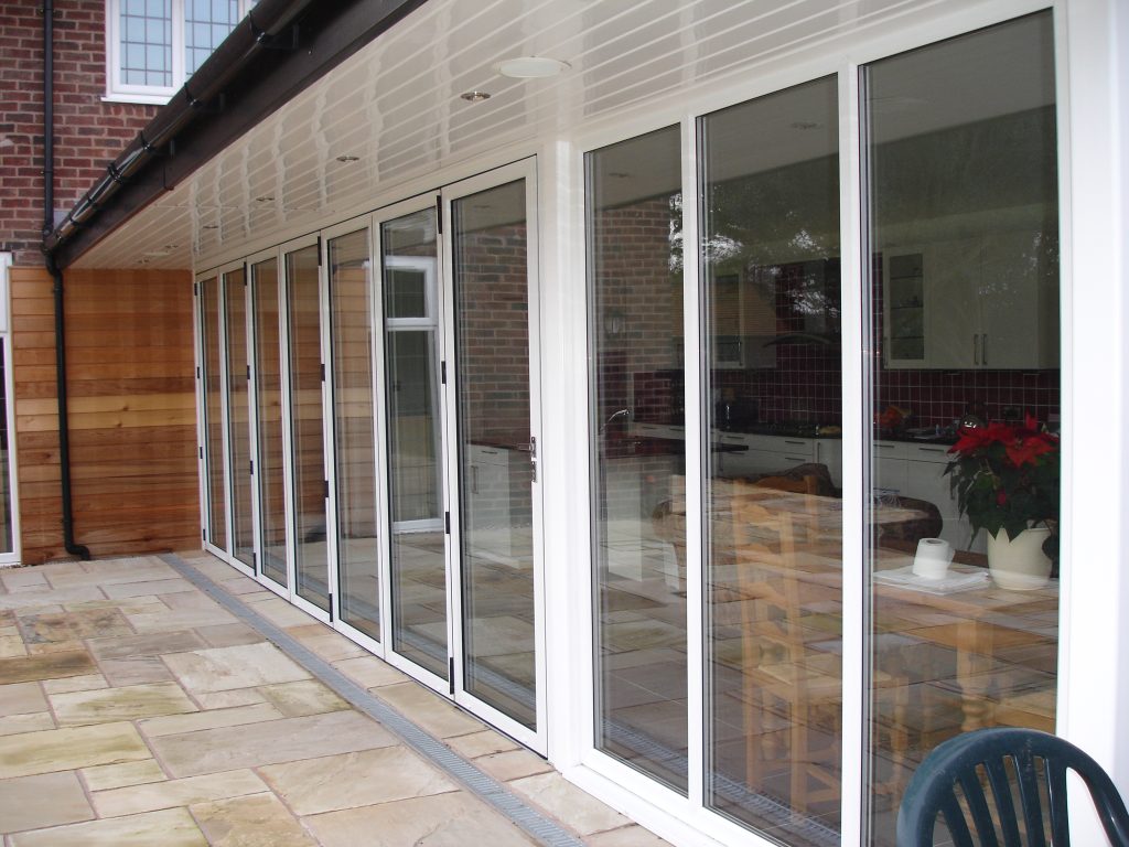 White-framed bi-fold doors opening onto a natural stone patio