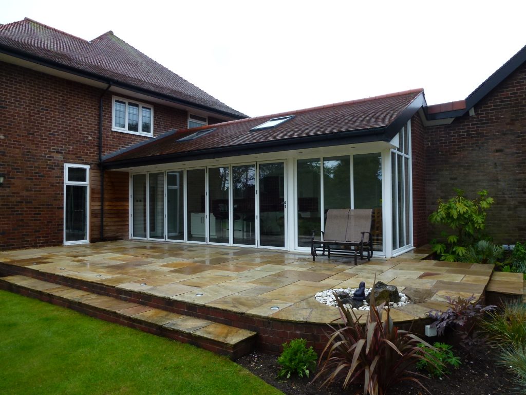 Finished single-storey rear extension with white bi-fold doors, tiled roof and Indian stone patio